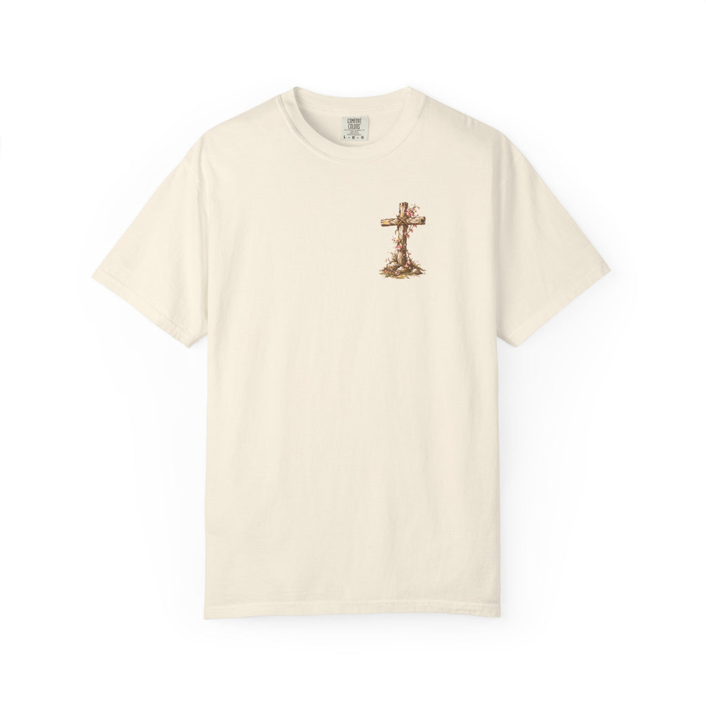An off-white short-sleeve crewneck t-shirt featuring a small graphic of a wooden cross decorated with dried flowers on the left chest, displayed against a solid white background.